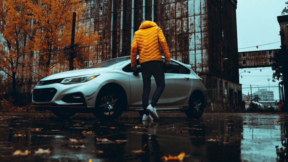 Street photo with a parked car and a person walking in front of it